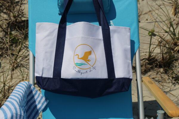 A beach chair with an embroidered bag on it.